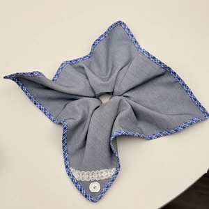 Detailed macro view of the blue denim fabric hair tie with white lace trim and button detail