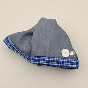 Detail of grey twill fabric hair tie with blue plaid trim and white pearl bead accents