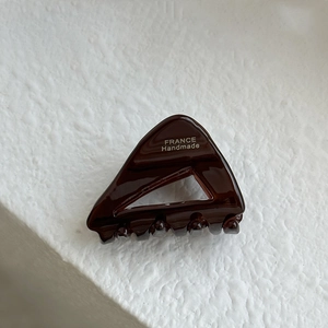 Detailed macro view of dark brown acetate triangle hair claw with silver handmade text