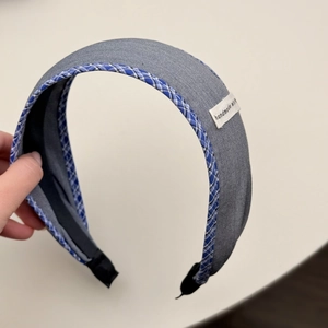 Close-up of grey fabric headband with blue checkered edges and handmade woven label