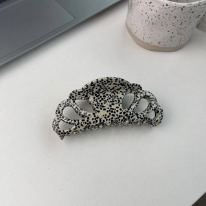Grande pince à cheveux à pois noirs et blancs dans un décor moderne minimaliste