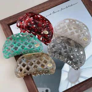 Detail of five hollow waffle acetic hair clips with gold logo on a vintage mirror