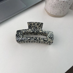Détail d'une grande pince à cheveux en acétate avec motif terrazzo sur un bureau
