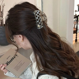 Hollow waffle checkered acetate hair claw clip in grey worn by a model in a side view