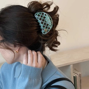 Close-up of mint green marble hollow hair claw clip worn on a messy bun hairstyle
