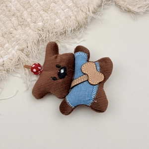 Close-up of brown corduroy teddy bear hair clip with denim overalls and bow detail