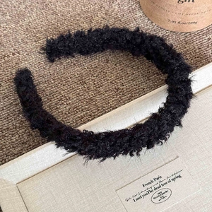 Gros plan d'un serre-tête en laine d'agneau noire duveteuse avec une texture de luxe douce