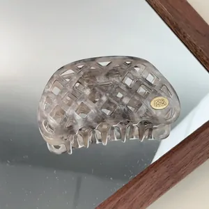 Macro detail of hollow waffle weave acetate hair claw in smoky grey marble finish