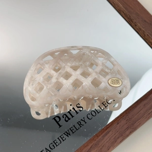 Macro view of hollow waffle pattern acetate hair claw clip with golden metal logo