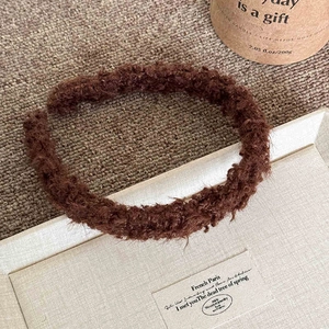 Détail de la texture douce en laine d'agneau marron foncé sur ce bandeau d'hiver chic