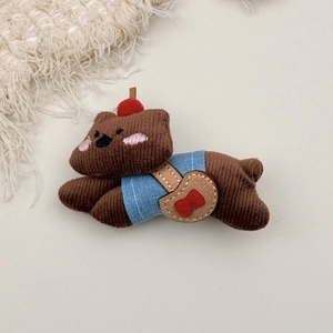 Detail of brown corduroy teddy bear hair clip with blue vest and red cherry accent