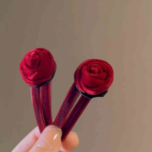 Detail view of two vintage wine red velvet rose hair clips with realistic petal textures