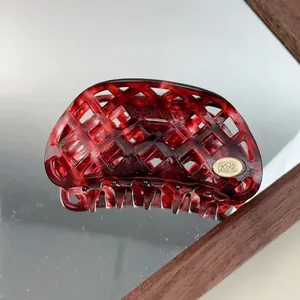 Detailed macro of dark red marble acetate hair claw clip with golden brand plate