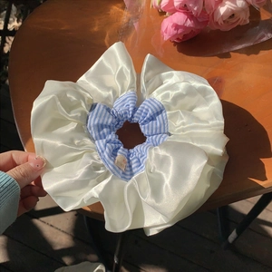 Oversized blue plaid and cream satin scrunchie shown on a wooden table outdoors