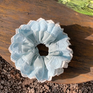 Détail du chouchou en satin bleu clair avec dentelle en cœur sur un support en bois