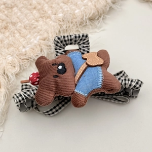 Detailed shot of teddy bear hair clip featuring brown corduroy and blue overalls