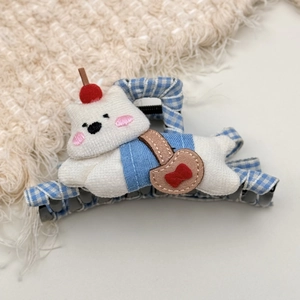 Close-up of cute plush white cat hair claw with blue plaid and cherry detail