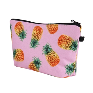 Detailed view of pink trapezoid makeup bag with vibrant pineapple digital print and black zipper