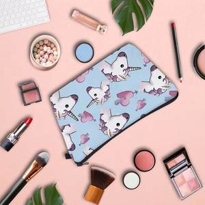 Detailed flat lay of unicorn print makeup bag with cosmetics on a pink background
