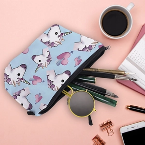 Flat lay of unicorn makeup bag with sunglasses and stationery on a pink desk