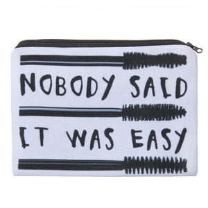 Detail of canvas makeup bag with zipper featuring black slogan and mascara brush graphics