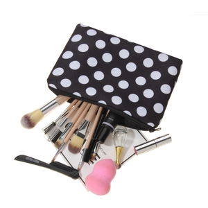 3D black and white polka dot makeup bag with various cosmetic brushes on a white background