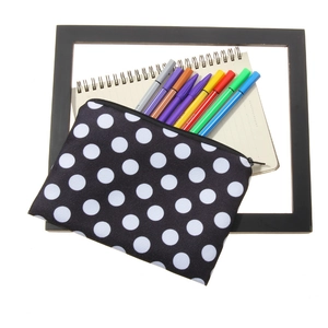 Polka dot cosmetic bag for makeup and stationery shown with colored pens on white background