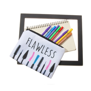 White canvas makeup bag with FLAWLESS print and eyelash brush design on a desk