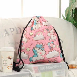 Pink drawstring backpack with unicorn print and black cord straps in a lifestyle setting