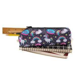 Detail of unicorn print oxford makeup bag shown with notebooks and a wooden ruler