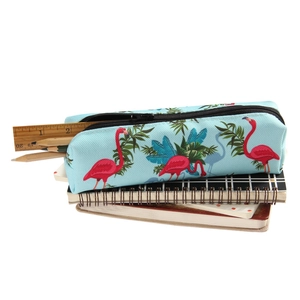 Oxford flamingo makeup bag with tropical leaf print and pencils on notebook stack