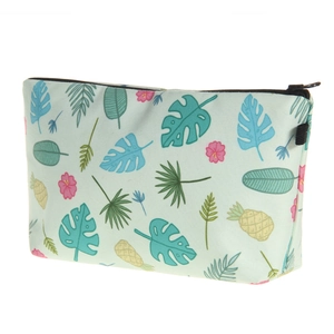 Detail view of tropical leaf and pineapple print on a blue cute makeup bag with zipper