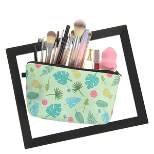 Cosmetic bag with tropical leaves and pineapple print shown with makeup accessories