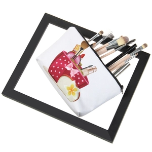 White canvas makeup bag with floral print and brushes shown against a frame background
