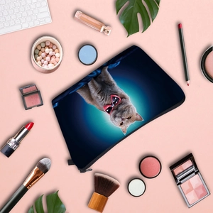 Blue makeup bag featuring a cat with a red bow, surrounded by cosmetics on pink background