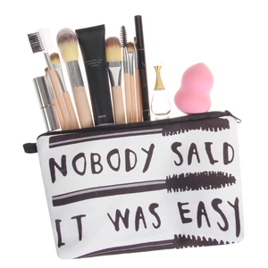 White canvas makeup bag with black letter print and brushes in a clean display