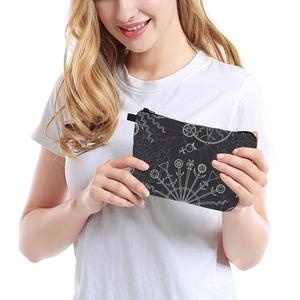 Close-up of black travel pouch with white astrological prints held by a model