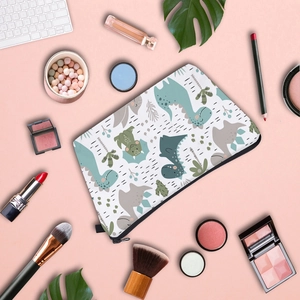Overhead view of a dinosaur print waterproof cosmetic bag with makeup accessories around