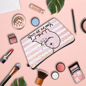 Detailed flat lay of pink striped dinosaur cosmetic bag with makeup and keyboard items