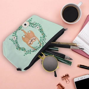 Water-resistant digital print sloth makeup bag on pink desk with travel accessories