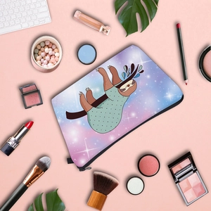Flat lay of a starry sloth makeup bag surrounded by lipstick and brushes for travel