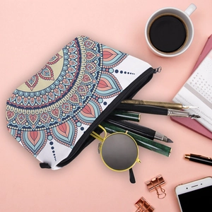 Mandala pattern travel makeup bag with pens and sunglasses on a pink background