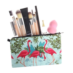 Cosmetic bag with pink flamingo print featuring brushes and makeup accessories inside