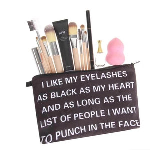 Portable black canvas makeup bag with white lettering filled with cosmetic tools