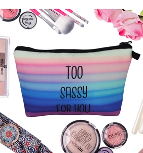 Rainbow striped makeup bag with Too Sassy For You text among cosmetics and flowers