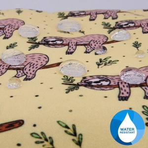 Close-up of water resistant floral cosmetic bag material with sloth print and water drops