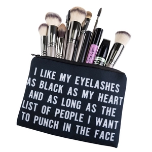 Trousse à maquillage noire en toile avec texte blanc et pinceaux sur fond blanc épuré