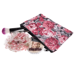 Floral makeup bag with red rose prints on black canvas, featuring brushes and powder