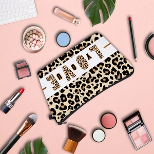 Leopard print makeup bag with LOVE print on a pink desk background with cosmetics