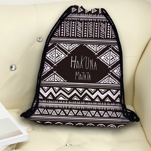 Drawstring backpack with geometric tribal patterns and Hakuna Matata text on beige sofa